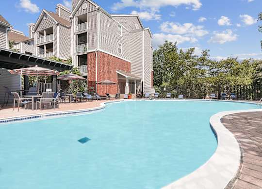 A large swimming pool in front of a multi-story apartment building.