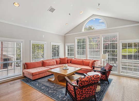 A sunroom with a red couch and a wooden table.