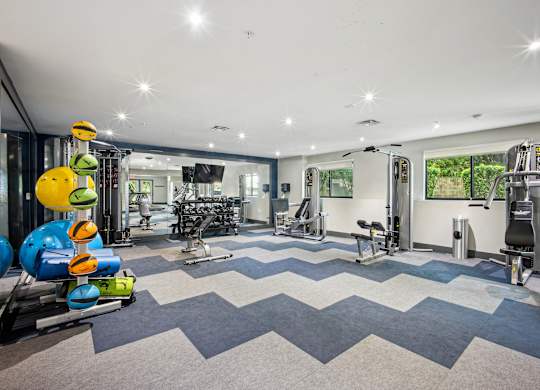 A gym with a variety of equipment including treadmills, weights, and exercise machines at Elme Bethesda, Bethesda, 20814