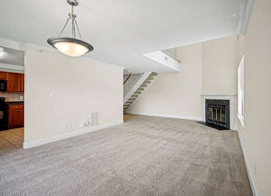 A large, empty room with a carpeted floor and a fireplace at Elme Bethesda, Bethesda, 20814