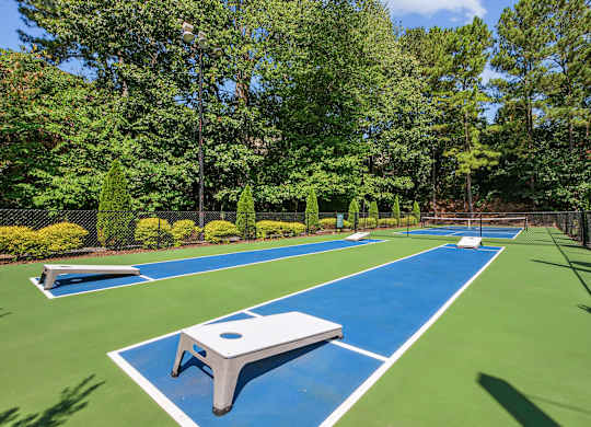 A blue and green tennis court surrounded by trees.