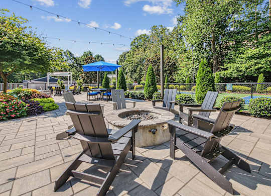 A patio with four chairs and a table with a fire pit in the middle.