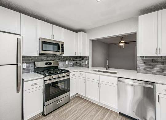 A modern kitchen with white cabinets and stainless steel appliances.