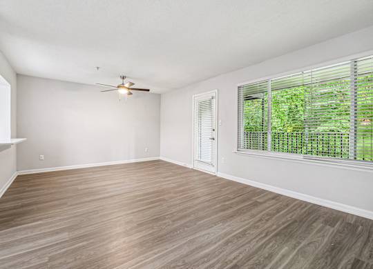 A room with a ceiling fan and a window with blinds.