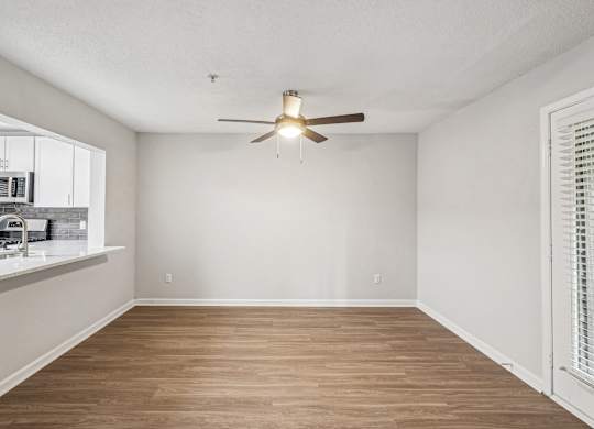 A room with a ceiling fan and wooden flooring.