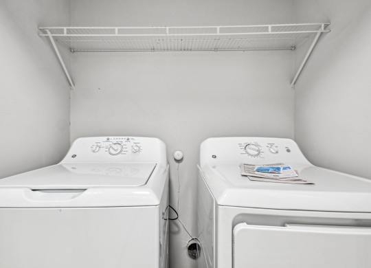 Two white washing machines in a small laundry room.