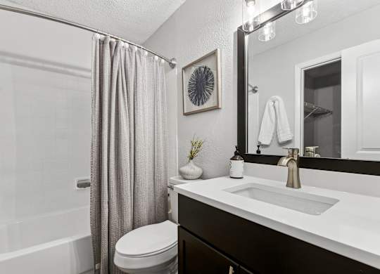 A bathroom with a white sink, toilet, and a shower with a grey curtain at Elme Druid Hills, Atlanta, Georgia