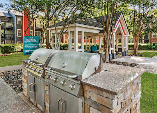 A large outdoor grill is situated on a stone platform in a grassy area at Elme Druid Hills, Atlanta, Georgia