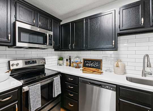 A kitchen with black cabinets and a white backsplash at Elme Druid Hills, Atlanta, Georgia