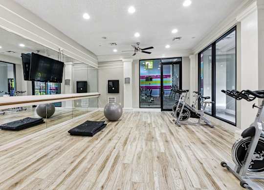 A spacious room with wooden flooring and exercise equipment.