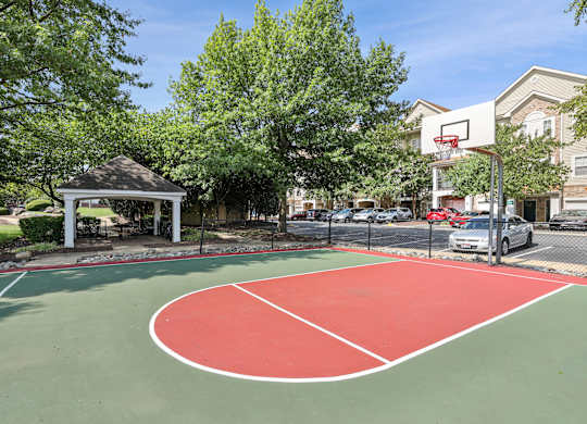 A basketball court with a red and green surface and a white and red hoop at Elme Dulles, Herndon, VA