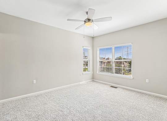 A room with a ceiling fan and carpeted floor.