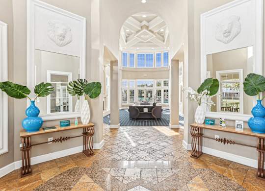A hallway with a tiled floor and two blue vases with green plants on top at Elme Dulles, Herndon, VA