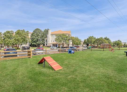 A park with a red bench and a blue playground equipment at Elme Dulles, Herndon, VA
