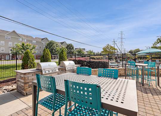 A patio with a table and chairs overlooking a grassy area and apartment buildings at Elme Dulles, Herndon, VA