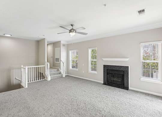 A spacious living room with a fireplace and a staircase.