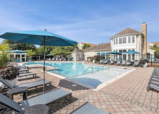 A large outdoor swimming pool surrounded by lounge chairs and umbrellas at Elme Dulles, Herndon, VA