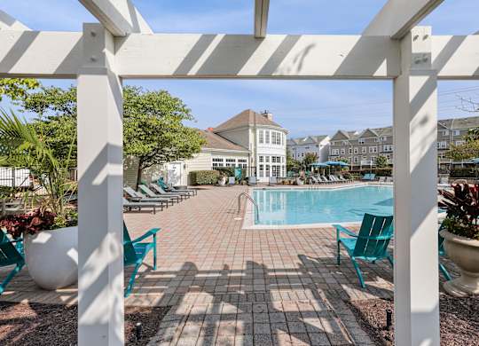 A pool surrounded by chairs and plants under a white pergola at Elme Dulles, Herndon, VA