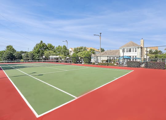 A tennis court with a red surface and white lines.