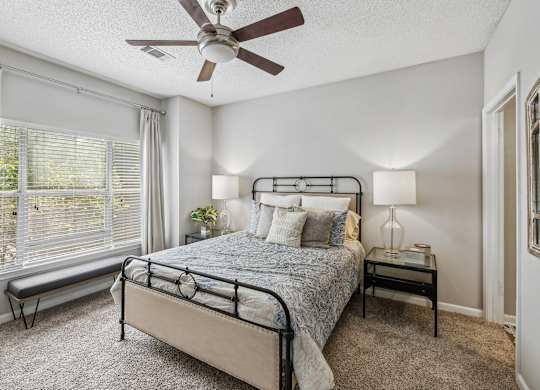 A bedroom with a bed, nightstand, and window.