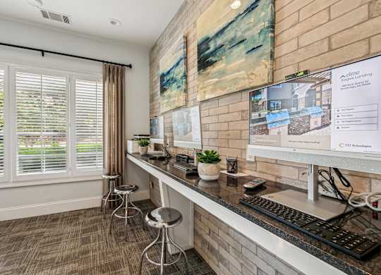 A room with a desk, a computer, and a painting on the wall.