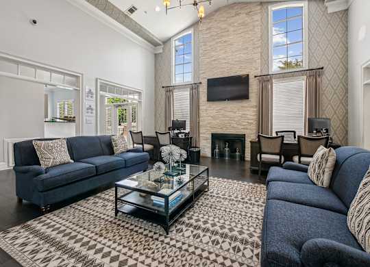 A living room with a blue couch and a glass coffee table.