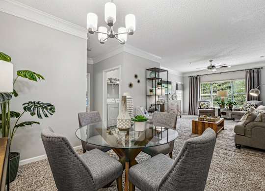 A modern dining room with a glass table and grey chairs.