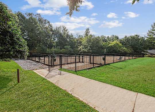 A black fence surrounds a green field.