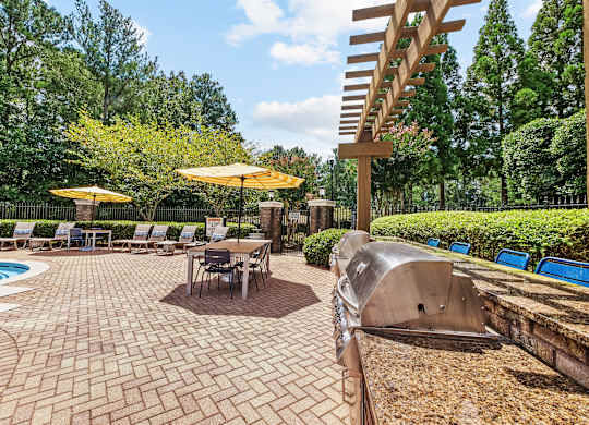 A patio with a table and chairs and a pool.
