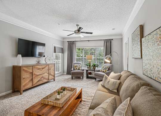 A living room with a brown sofa, a wooden coffee table, and a ceiling fan.