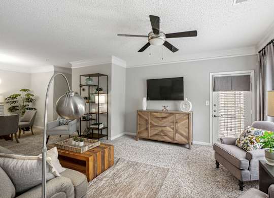 A living room with a grey couch, a wooden cabinet, and a TV on the wall.