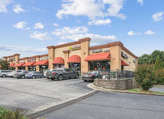 A parking lot in front of a store with a clear blue sky.