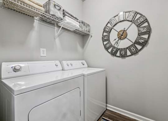 A laundry room with a washer and dryer and a clock on the wall.