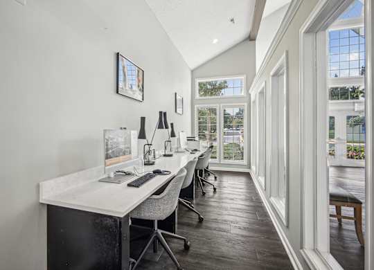 A white desk with a computer and a chair in front of a window.