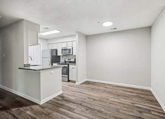 A kitchen with a refrigerator, microwave, oven, and sink.