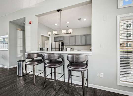 A kitchen with a bar area and three bar stools.