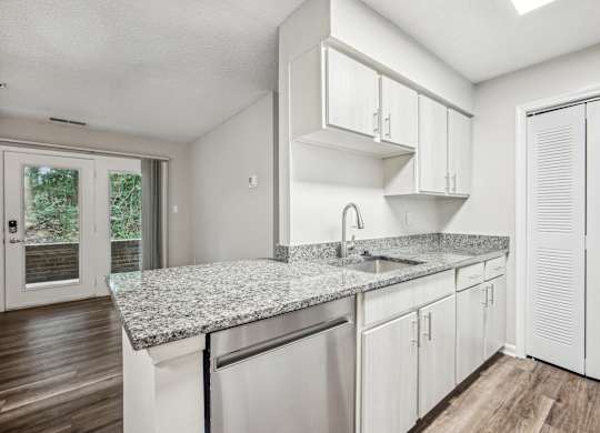 A kitchen with white cabinets and a granite countertop.