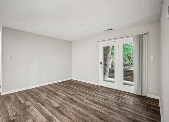 A room with a sliding glass door and wood flooring.