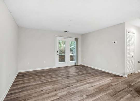 A room with wooden flooring and a sliding glass door.