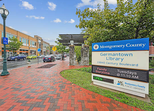 A sign for the Montgomery County Germantown Library is displayed on a brick walkway.