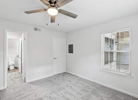 A room with a ceiling fan and a window with blinds.