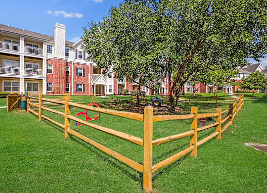 A red brick building with a white balcony and a yellow fence in front of it.