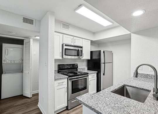 A modern kitchen with white appliances and a granite countertop.