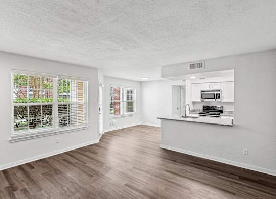 A spacious, empty room with wood flooring and white walls.