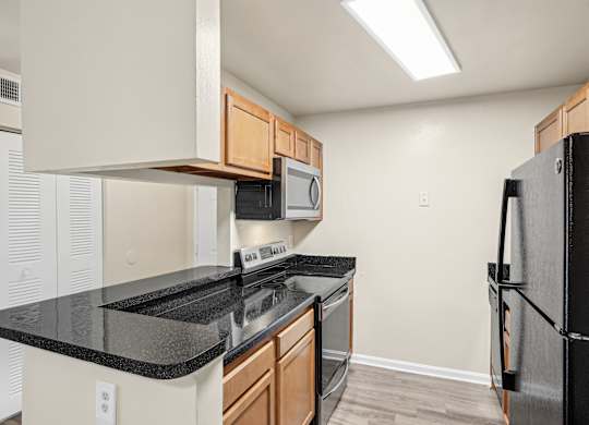 A kitchen with black countertops and a black refrigerator at Elme Leesburg, Virginia, 20176