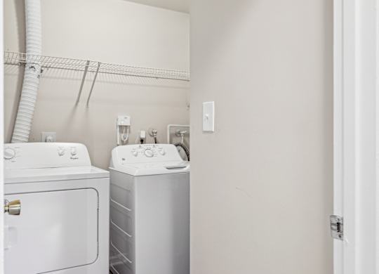 A white washing machine and dryer in a small laundry room at Elme Leesburg, Virginia, 20176
