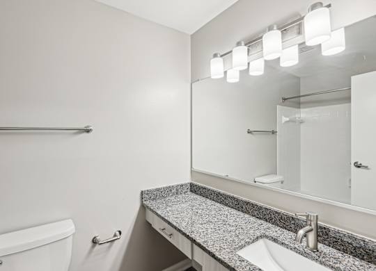 A bathroom with a toilet, sink, mirror, and lighting fixture at Elme Manassas, Manassas, 20109