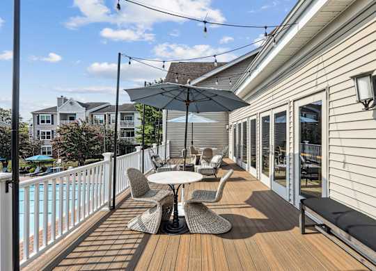 A patio with a table and chairs overlooking a pool.