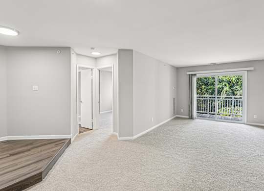 A spacious room with a carpeted floor and a balcony with a railing.