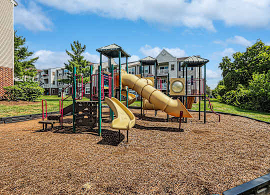 A playground with a yellow slide and a red and green structure.